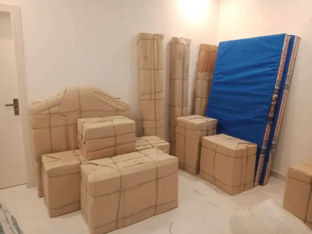 Packed cartons and a wrapped mattress in a room during a house shifting job